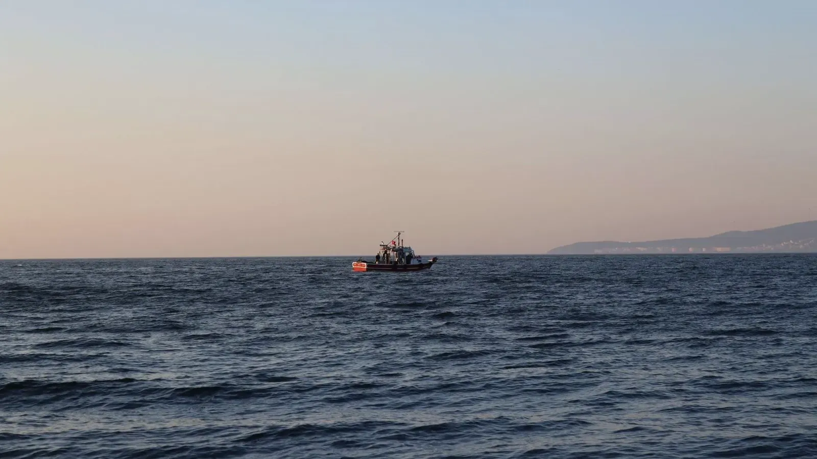 Pesquero de bajura navegando lejos de la costa al atardecer